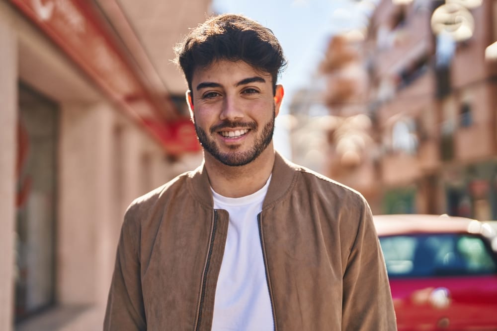 Confident young man with short dark hair smiling in the sunlight, symbolizing clear vision and confidence after LASIK eye surgery – LASIK Houston TX